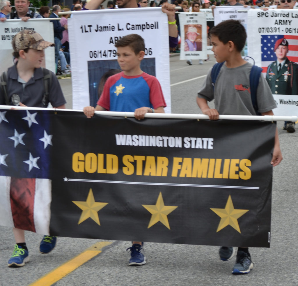 3 youth carrying Gold Star Families banner in parade