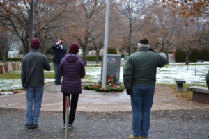 Community members salute wreaths around flagpole
