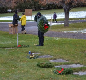 Volunteer saluting after placing wreath on headstone
