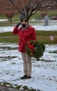 Volunteer saluting after placing wreath on headstone