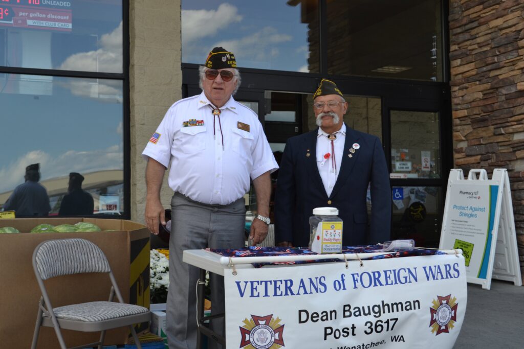 VFW members in uniform outside a grocery store with a Buddy Poppy fundraising table