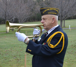 Larry Strozyk in uniform playing taps on a bugle.