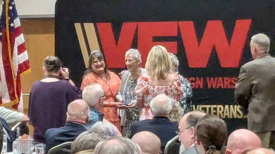 Group of people in front of VFW backdrop having their photo taken.