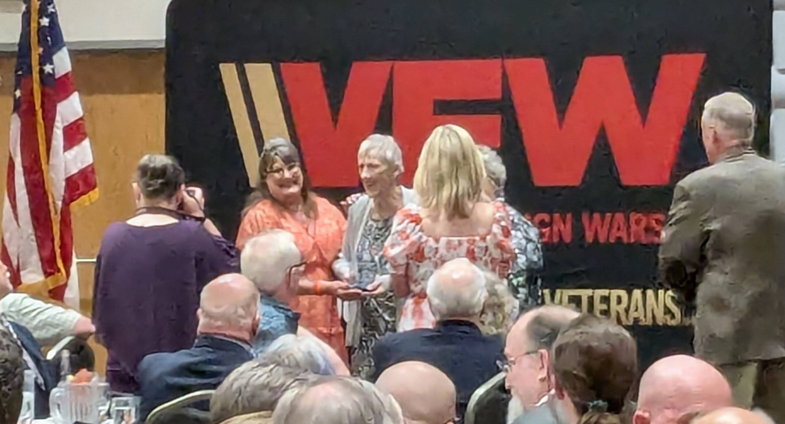 Group of people in front of VFW backdrop having their photo taken.