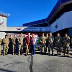 uniformed service members stand in front of their building