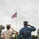 Armed Forces members in uniform saluting the American Flag