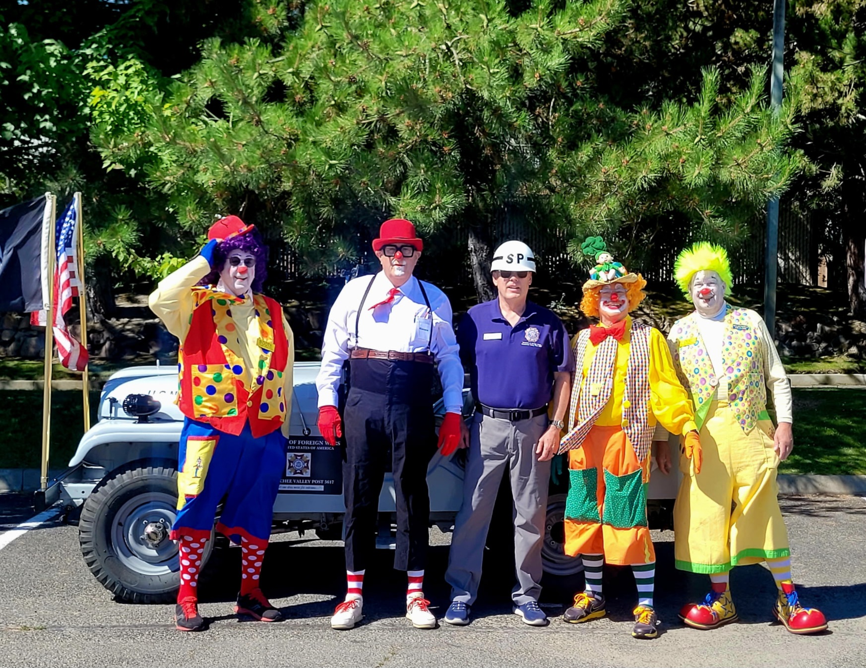 A group of four Clowns pose with VFW Post 3617 Commander Pieratt (center) in front of the jeep.
