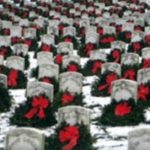 wreaths leaning on headstones in a snow-dusted graveyard