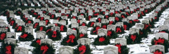 wreaths leaning on headstones in a snow-dusted graveyard